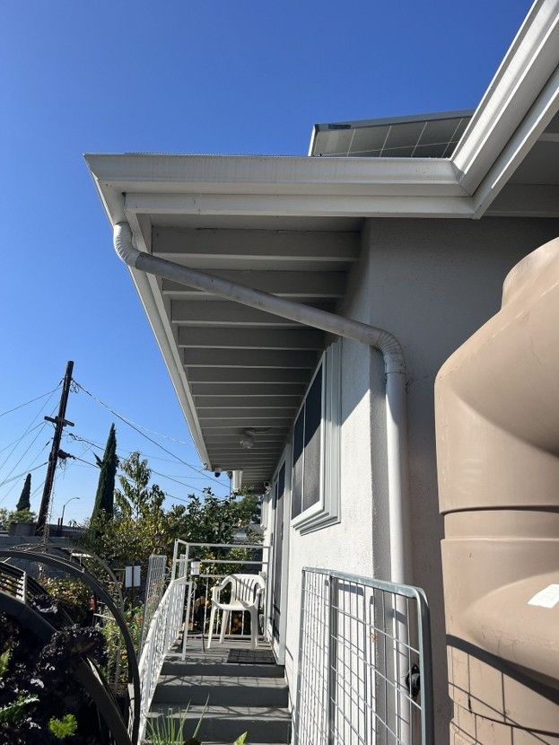 Side view of a house with white trim, a walkway with railing, and a blue sky overhead