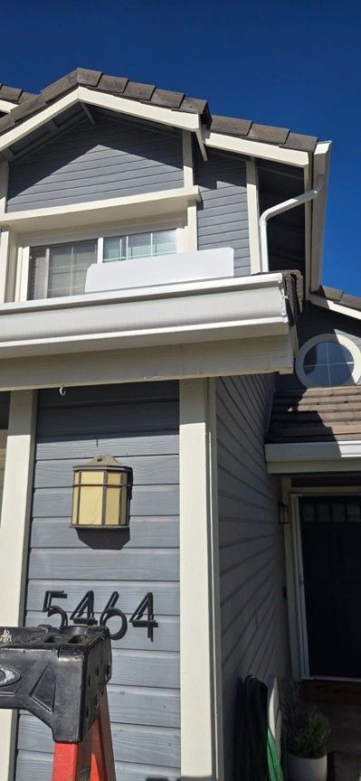 Gray two-story house exterior with address 5404 and a front window over the entrance.