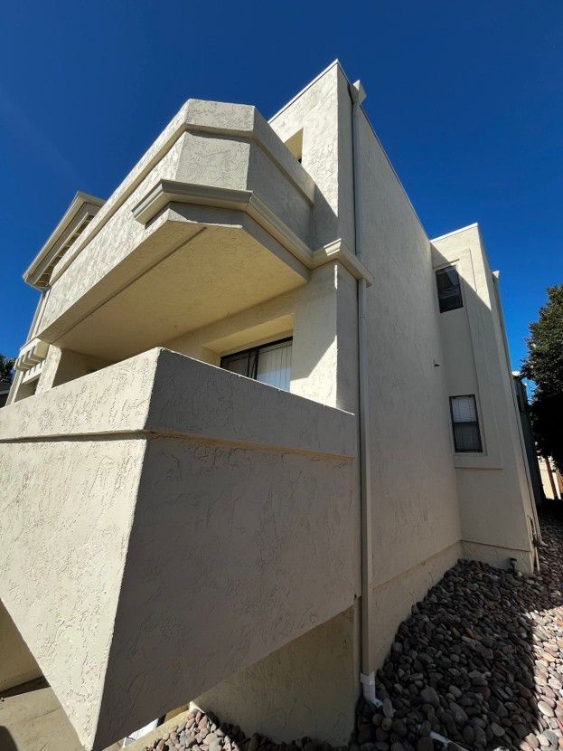 Modern beige concrete apartment building with angular balconies against a clear blue sky