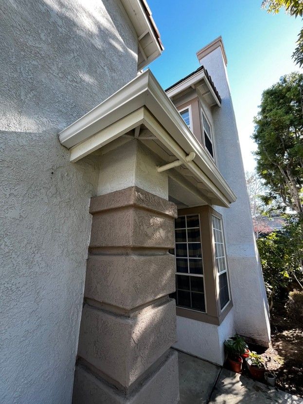 Front entrance of a gray house with stone column accents and a small covered porch