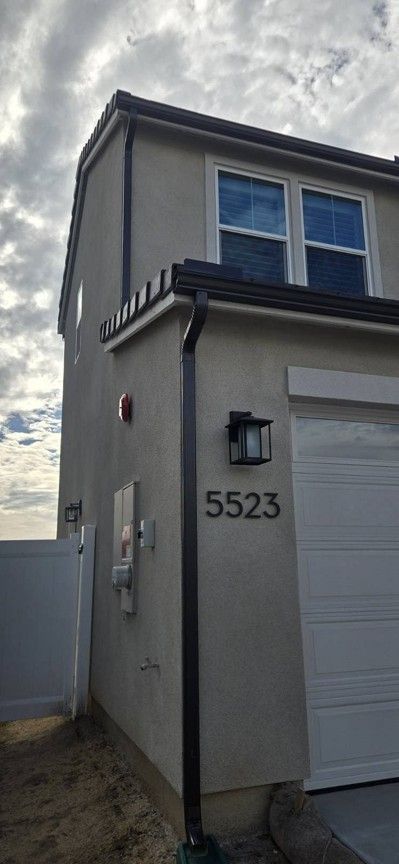 Front corner of a gray townhouse with white garage door and house number 5523 under a cloudy sky