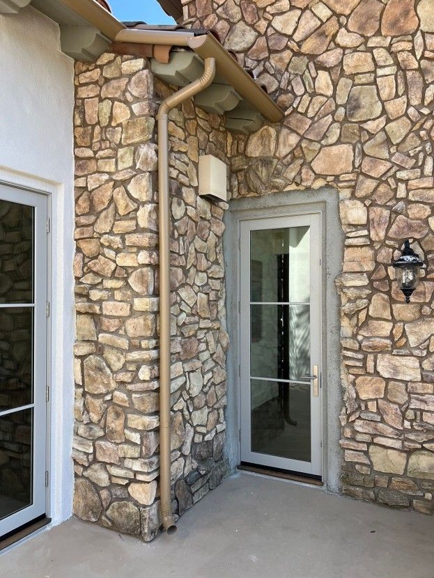 Stone exterior entryway with two glass doors and a wall-mounted lantern