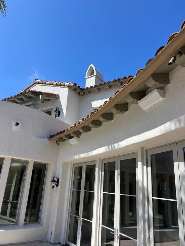 White stucco courtyard with arched windows, terracotta roof tiles, and blue sky above