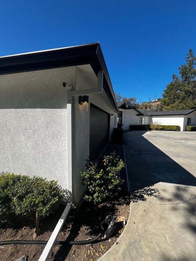 Outdoor view of a stucco house exterior with driveway, garage, and blue sky