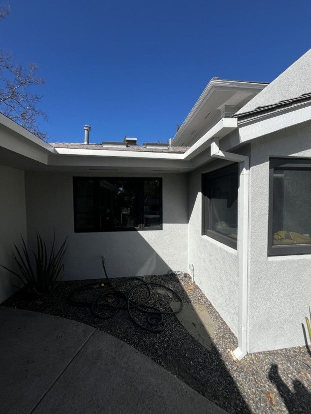 Courtyard with white stucco walls, black gravel, and a blue sky