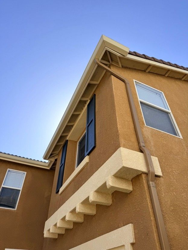 Low-angle view of a tan stucco apartment building against a clear blue sky