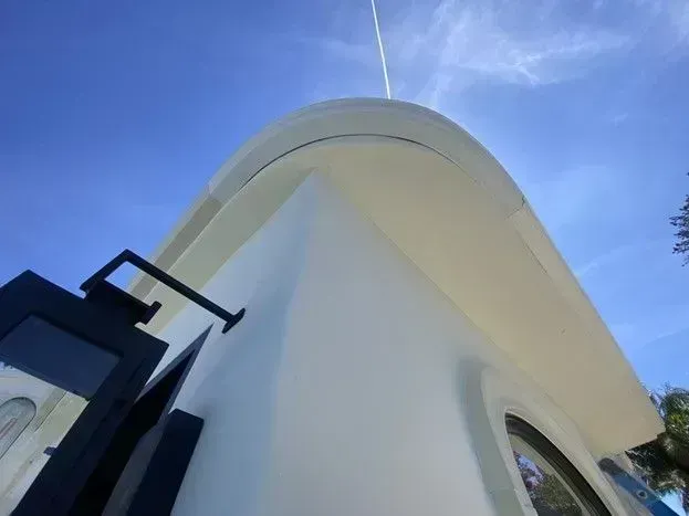 Curved white building facade against a blue sky, viewed from below