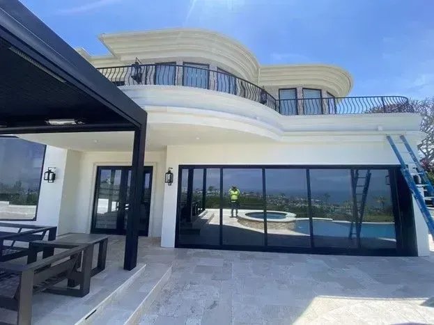 Modern white villa terrace with black-framed glass doors and balcony overlooking the sea