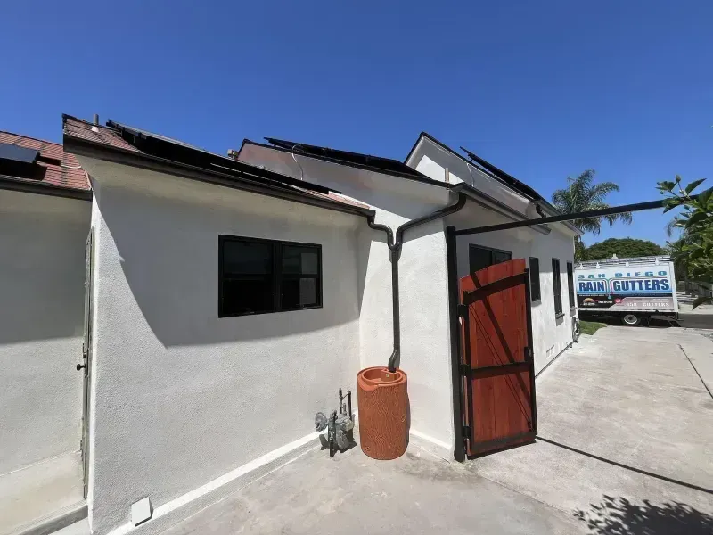 White building with a red gate and a small window under a bright blue sky.
