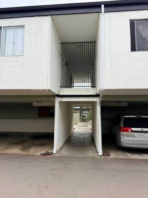 Apartment building with central walkway and parked cars on either side