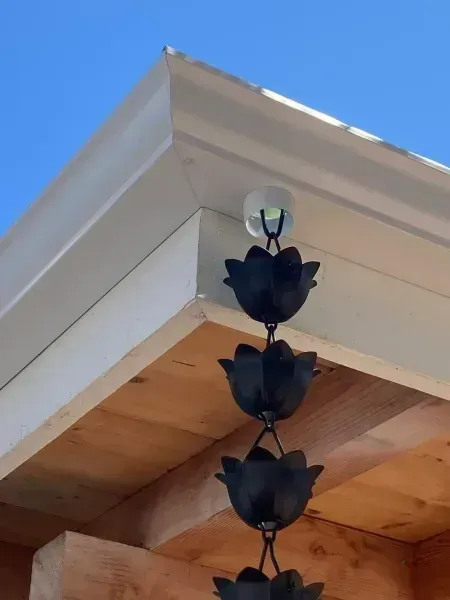 Black hanging decoration beneath a white roof eave against a blue sky
