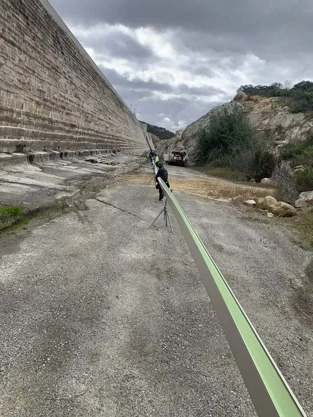 Person on a slackline stretched across a rocky ravine under a cloudy sky
