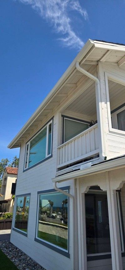White two-story house with large windows and balcony under a blue sky