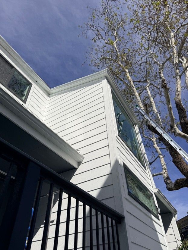 White house exterior with dark trim and leafless trees against a blue sky