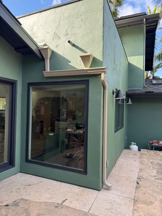 Modern stucco patio with large glass sliding door, small awning, and narrow concrete walkway