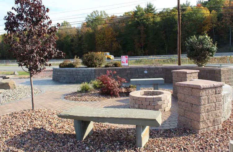 A stone bench is sitting next to a fire pit in a park.