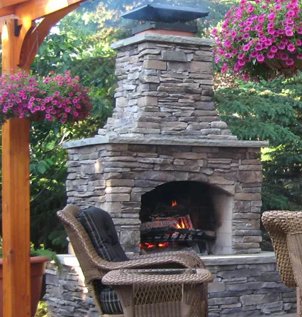 A wicker chair sits in front of a stone fireplace