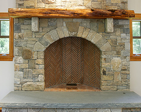A stone fireplace with a wooden door and a wooden mantle