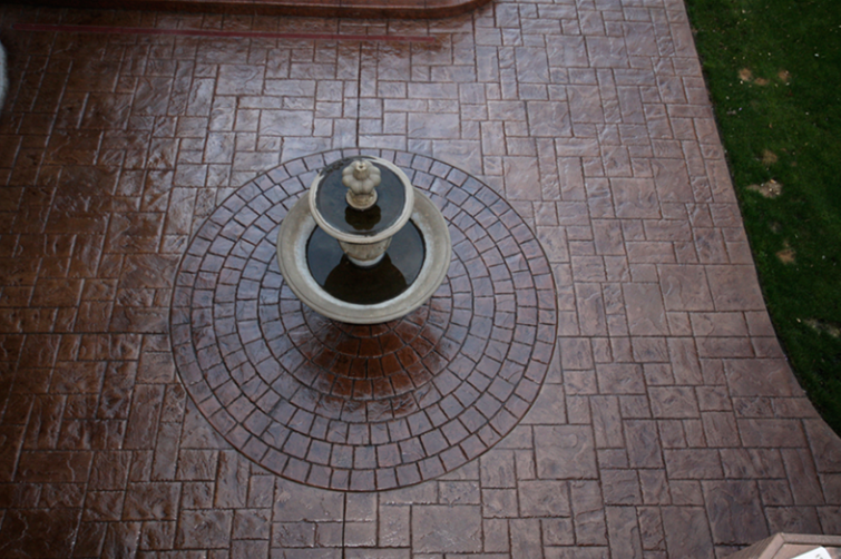 A fountain is surrounded by a circular pattern on a patio.