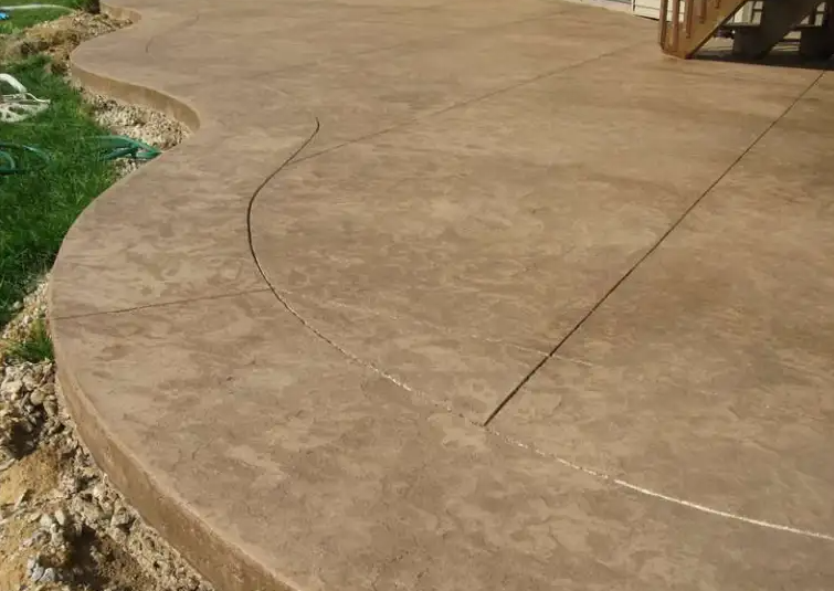 A concrete walkway with a curved edge and a staircase in the background.