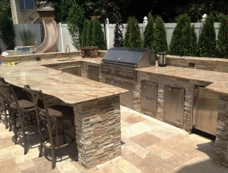 A large outdoor kitchen with granite counter tops and stainless steel appliances