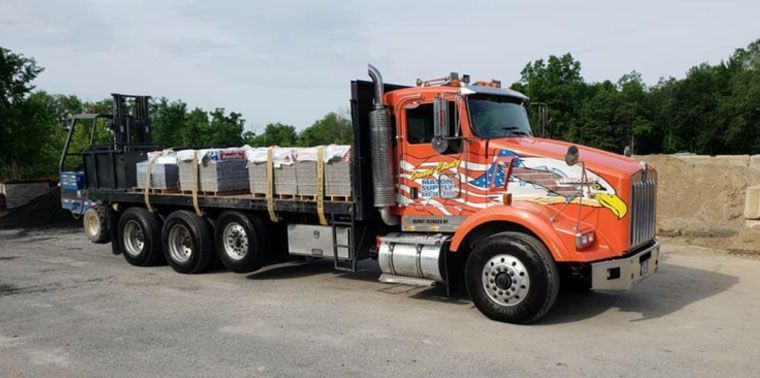 A red semi truck with a flatbed trailer is parked in a parking lot.