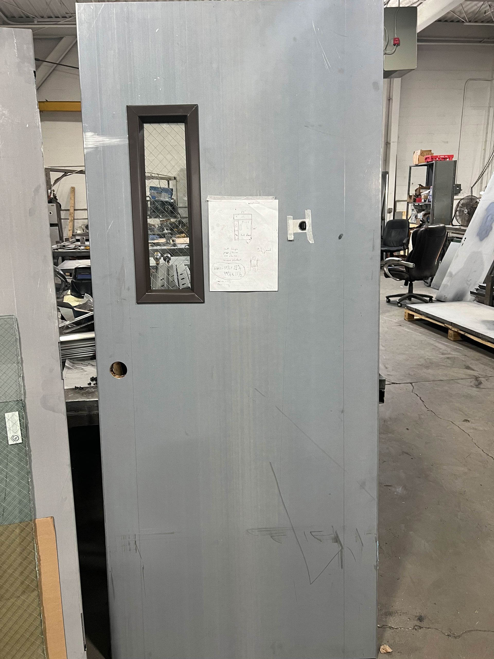A gray door with a window and a note on it