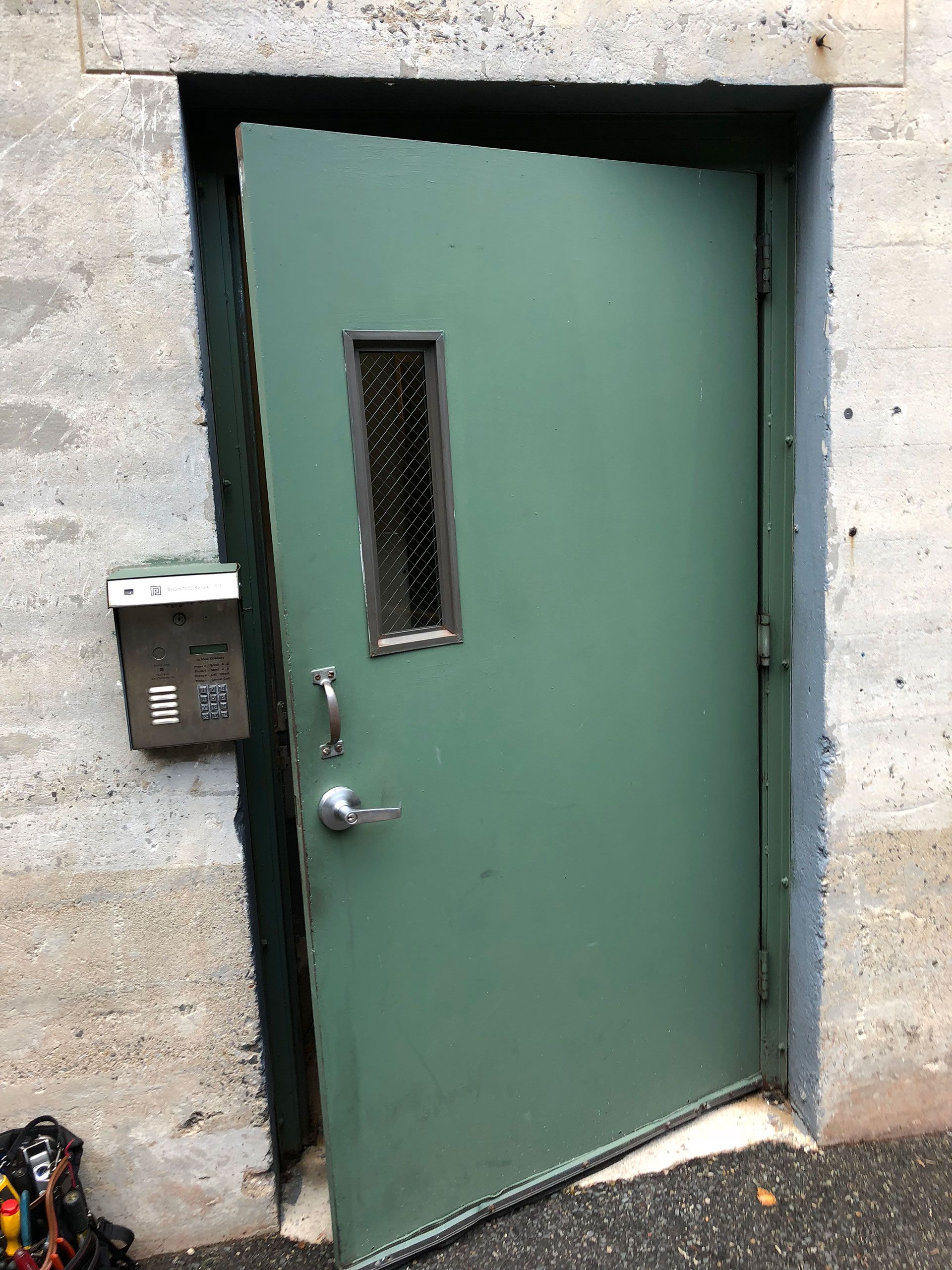A green door with a window and a mailbox on the side of a building