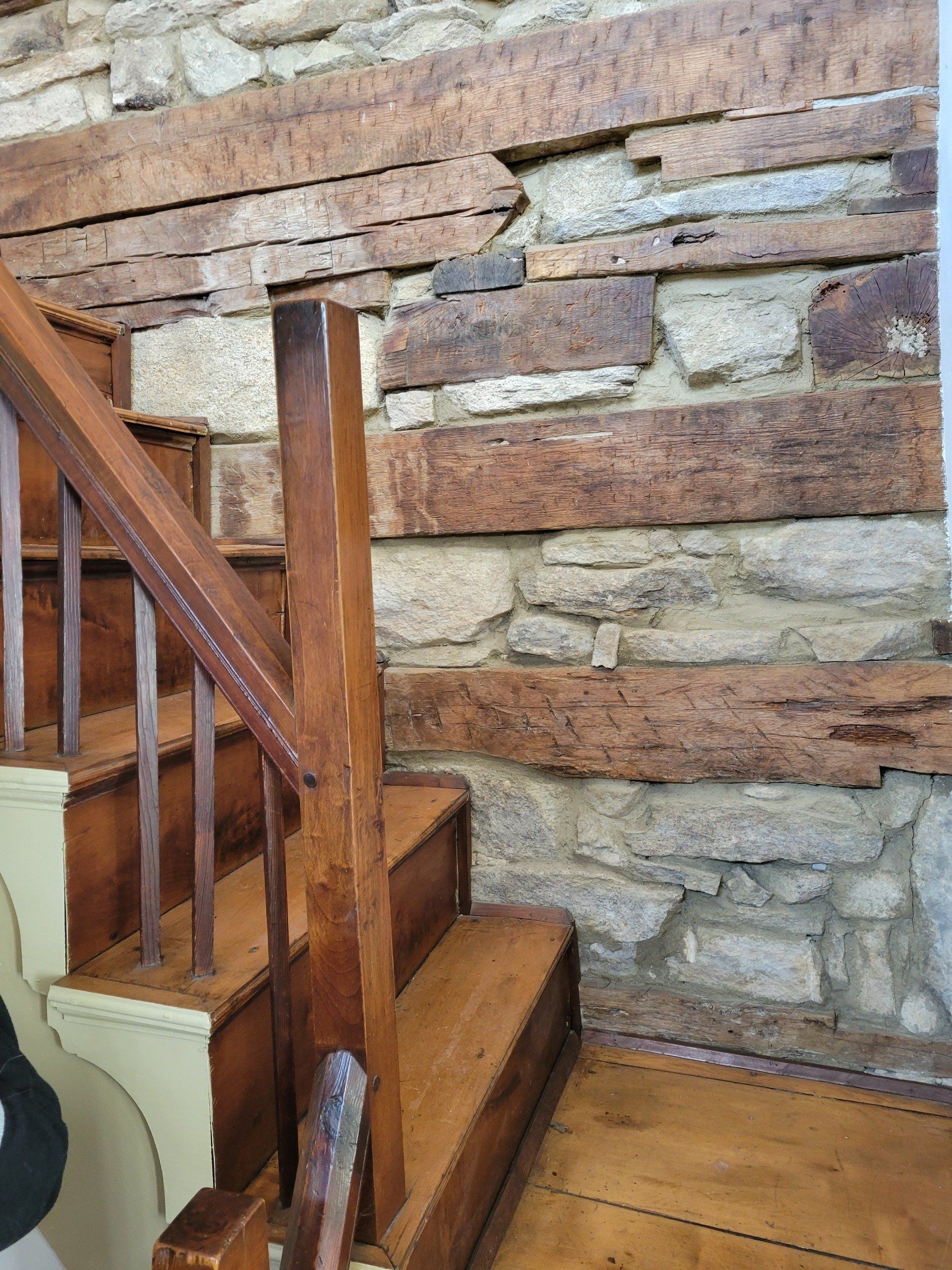 A wooden staircase with a stone wall behind it.