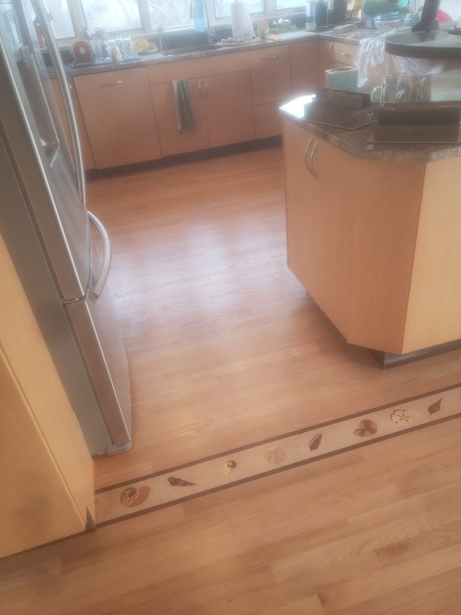 A kitchen with a wooden floor and a refrigerator.