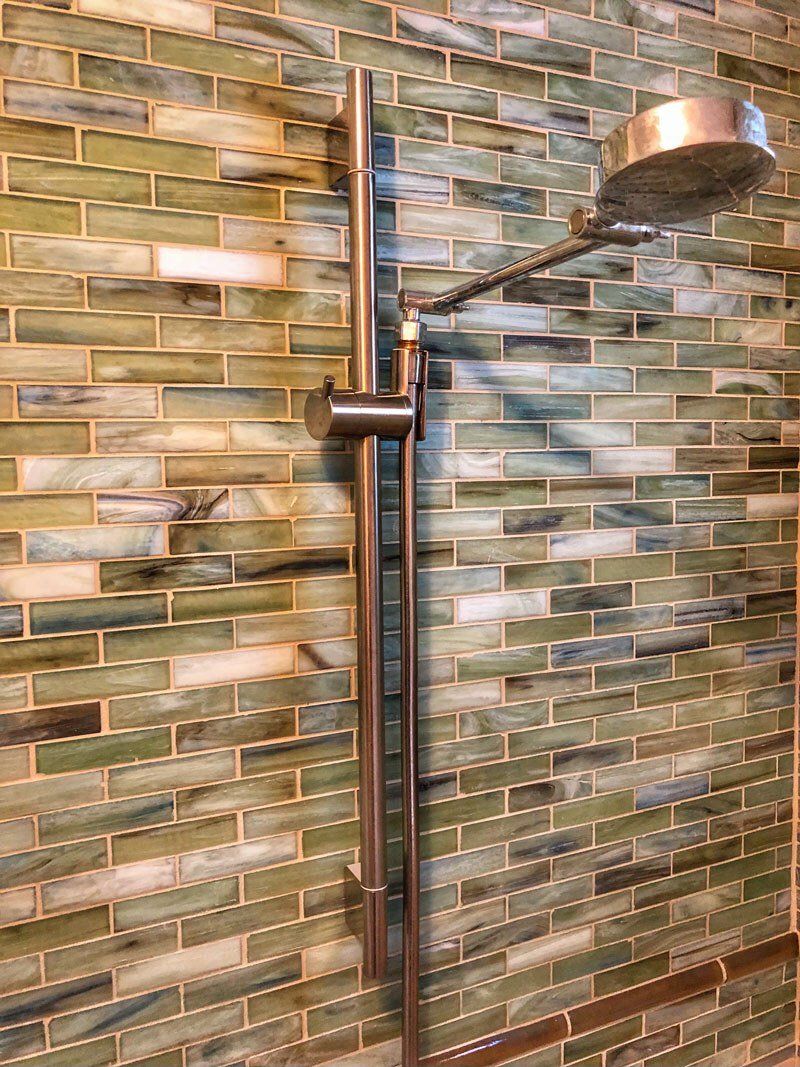 A shower head is hanging on a tiled wall in a bathroom.
