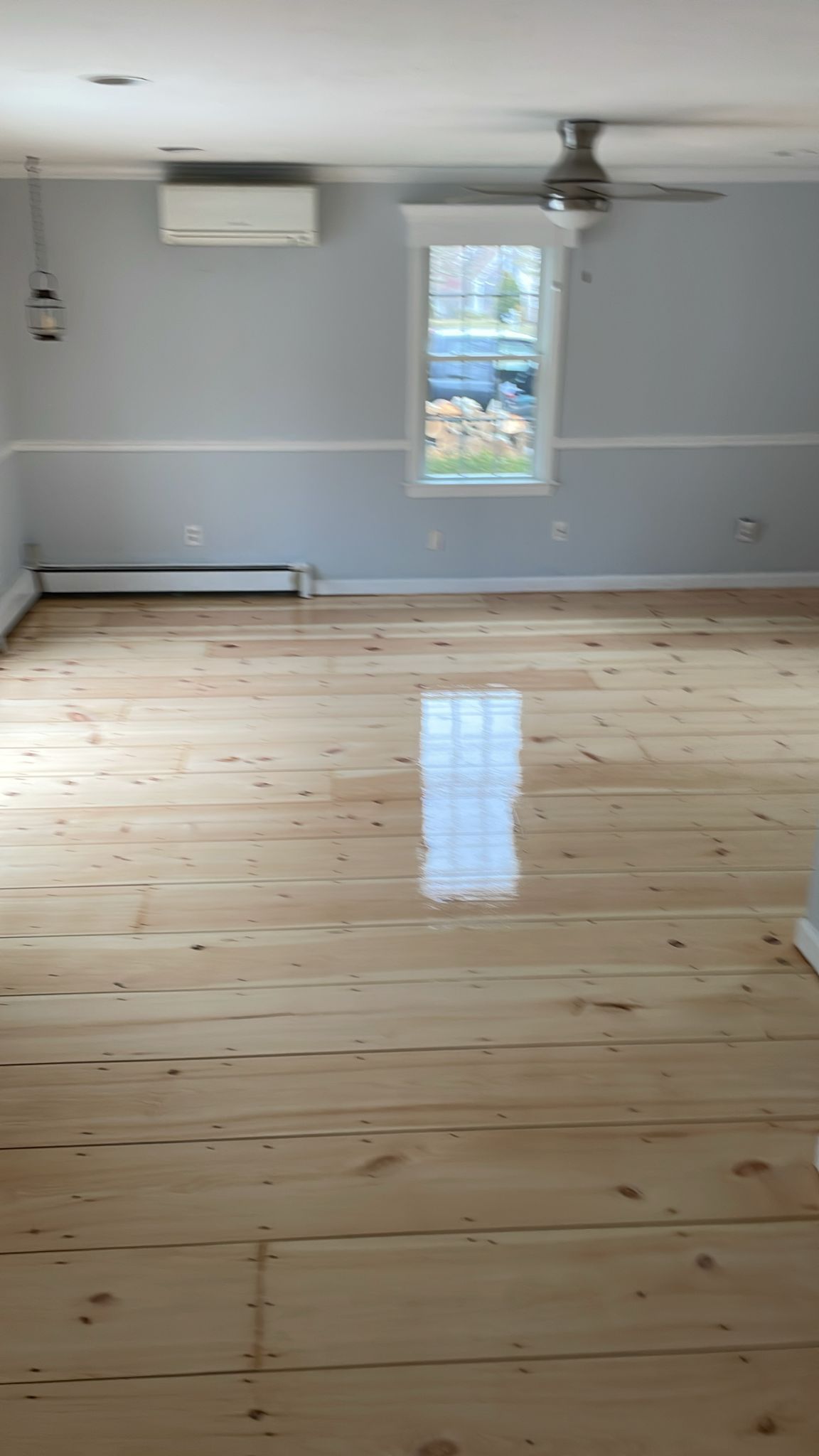 A living room with a wooden floor and a ceiling fan.