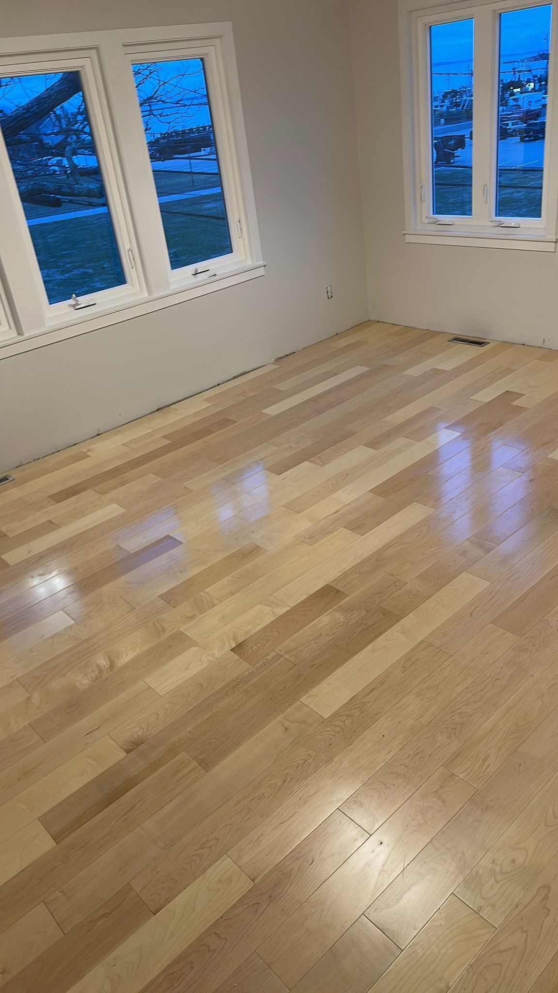 A room with hardwood floors and two windows.