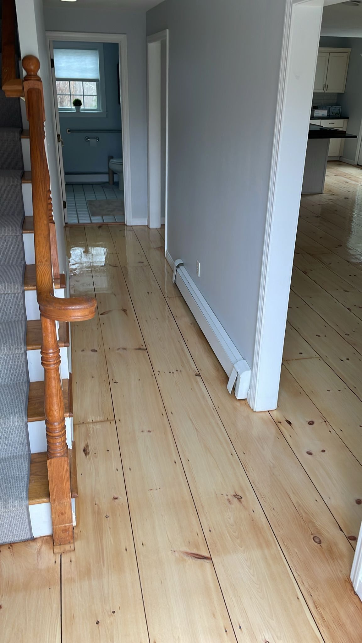 A hallway with wooden floors and stairs in a house.