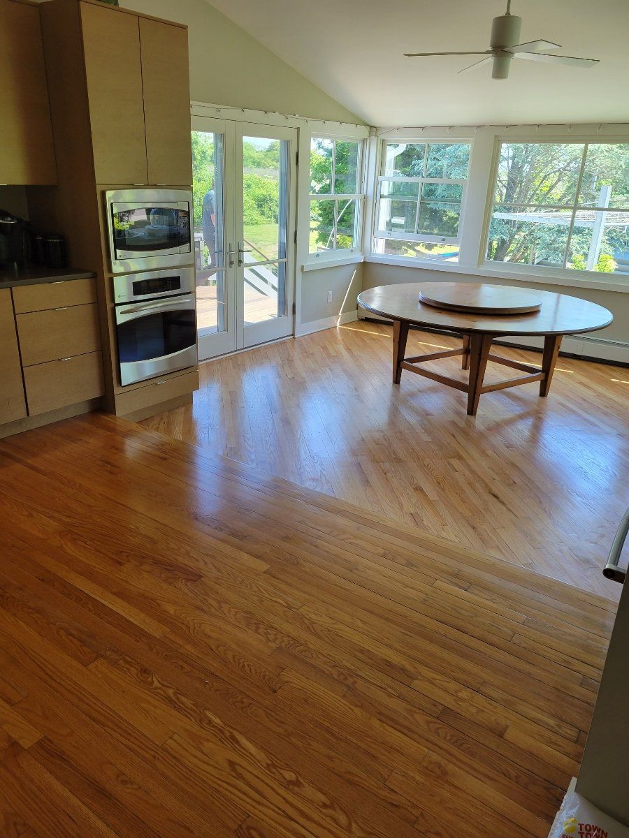 A living room with hardwood floors , a table and a ceiling fan.