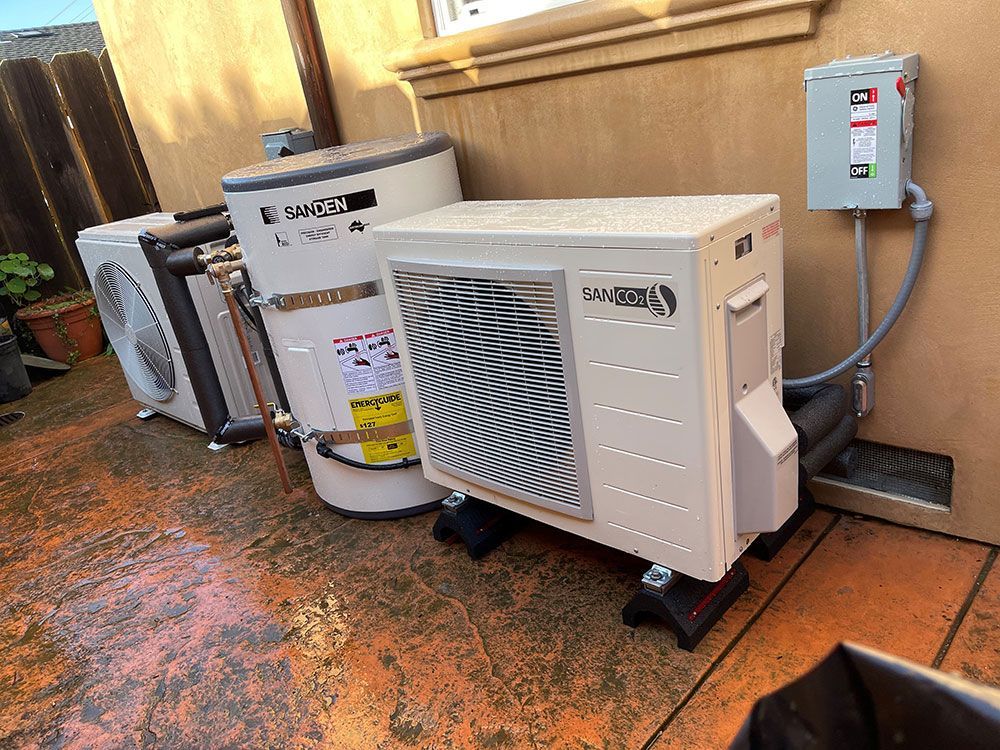 Outdoor mechanical equipment, including a heater, tank, and electrical box, is against a wall on a patio.