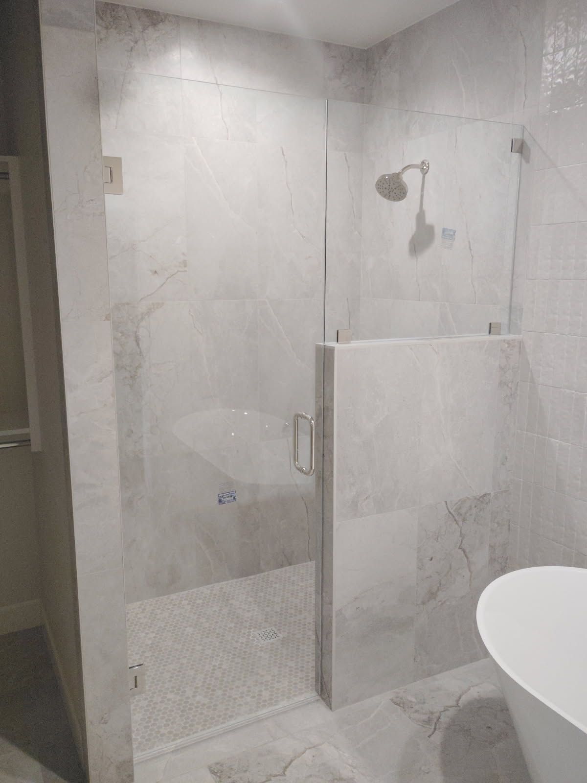 Small tiled bathroom with a glass shower door and partial view of a white sink.