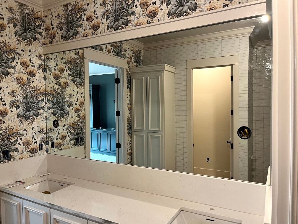Bathroom vanity with large mirror, floral wallpaper, and tiled walls above a sink and counter