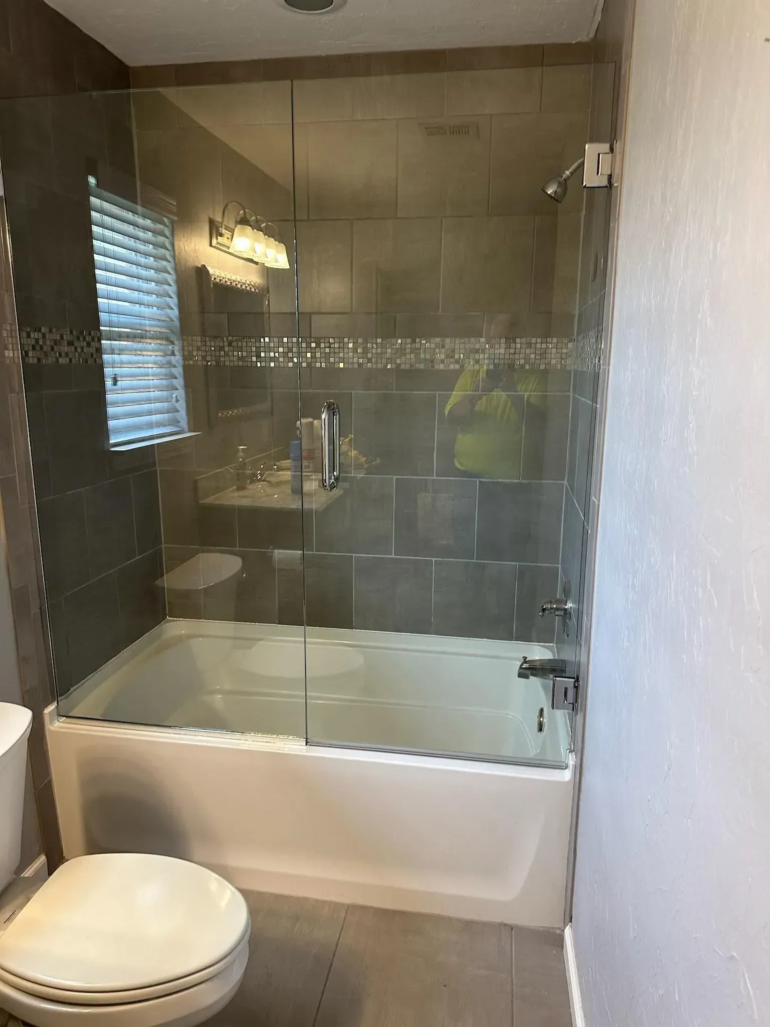 Small bathroom with a toilet and a glass-enclosed bathtub-shower combination.