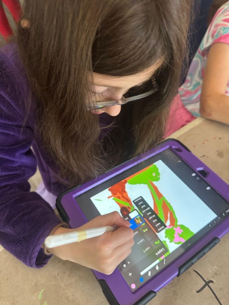 Girl with glasses drawing on a tablet with a stylus. Bright colors appear on screen; she wears a purple jacket.