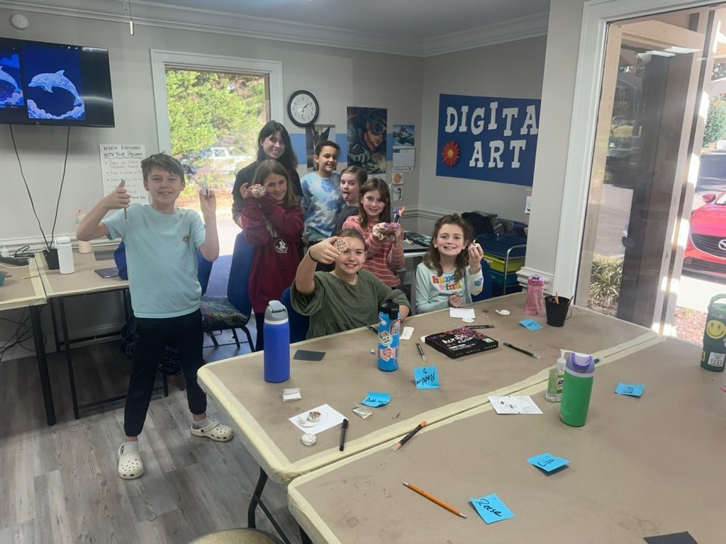 Kids giving thumbs up at a table with art supplies in a room with a 