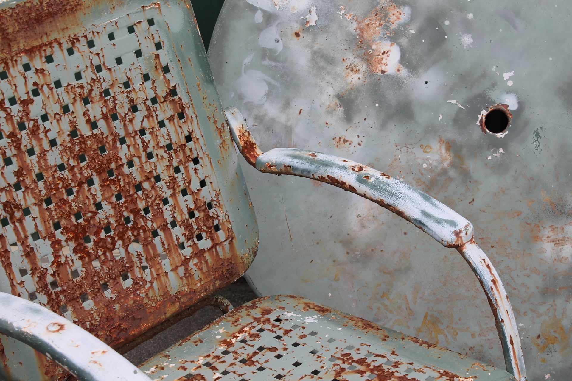 A rusty chair with a hole in the back of it
