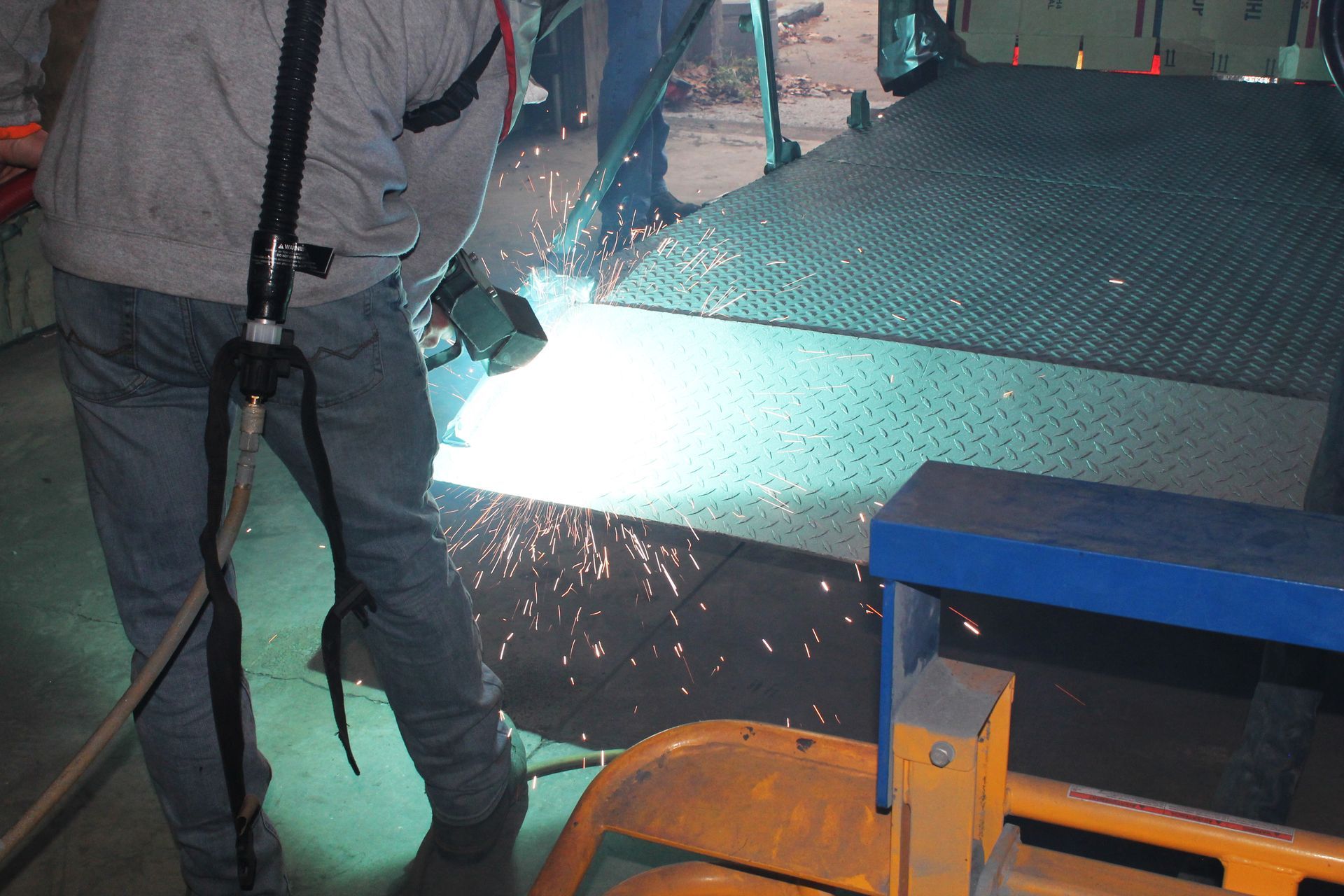 A man is welding a piece of metal in a dark room