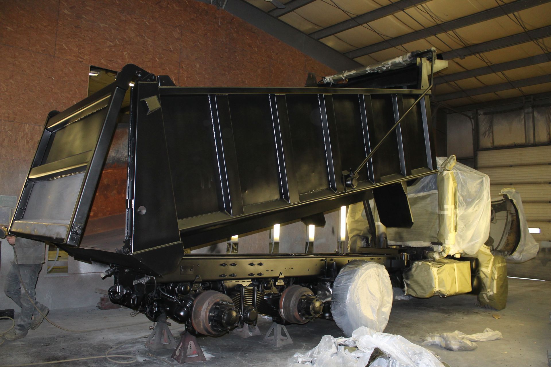 A dump truck is painted black in a warehouse