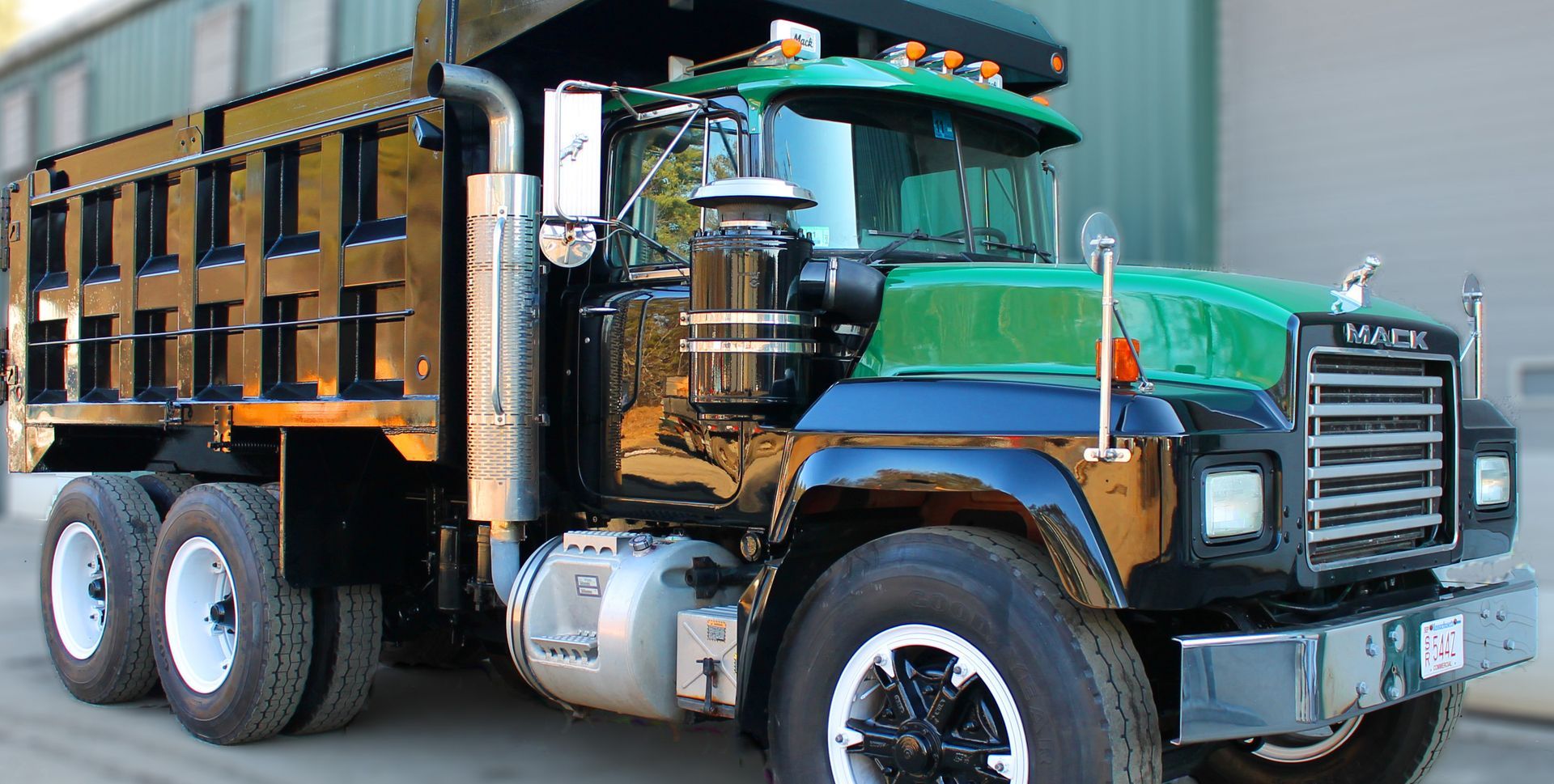A mack dump truck is parked in front of a building