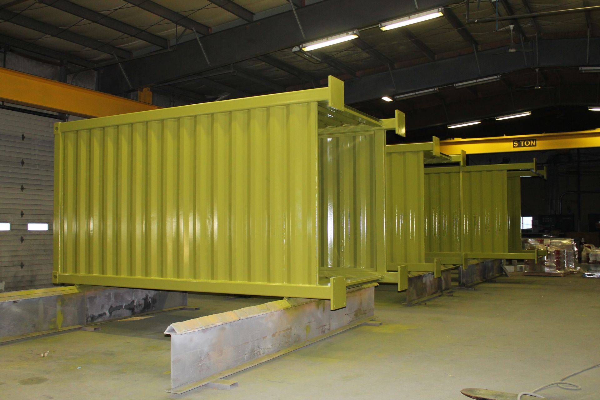 A row of yellow shipping containers are sitting in a warehouse.
