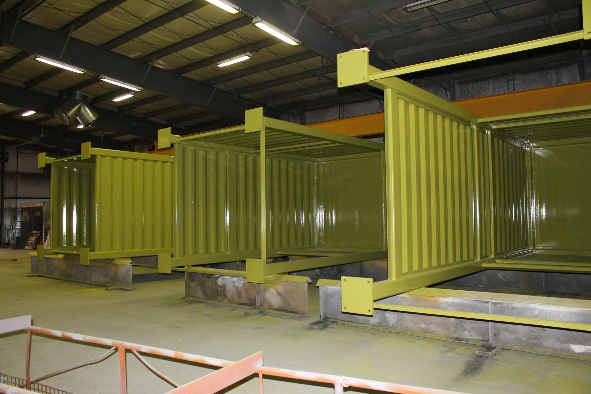 A row of yellow shipping containers are sitting in a warehouse.