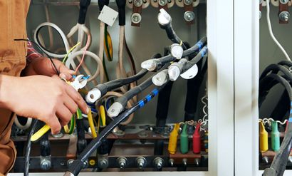 A person is working on an electrical box with a lot of wires.
