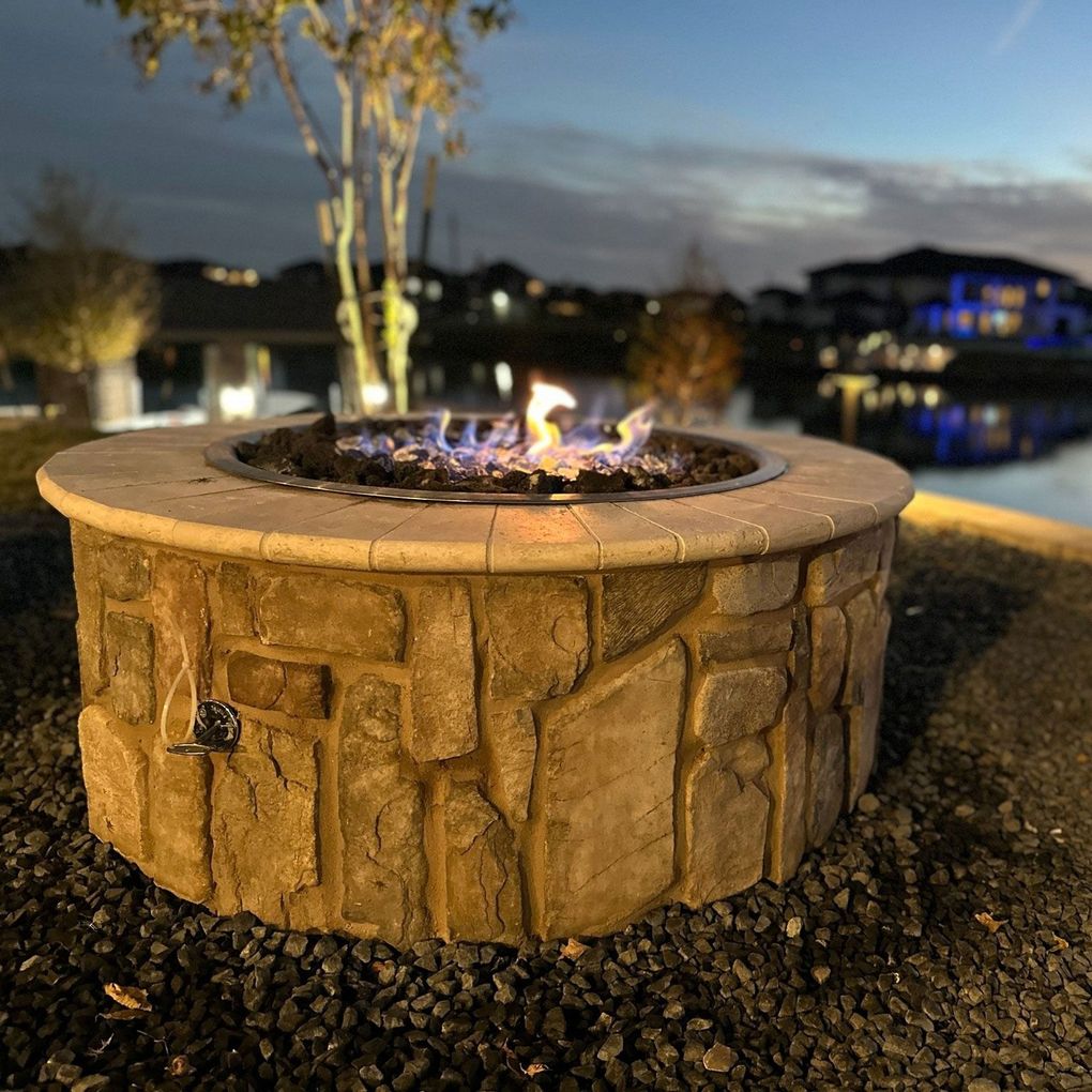 A fire pit is lit up at night with a house in the background