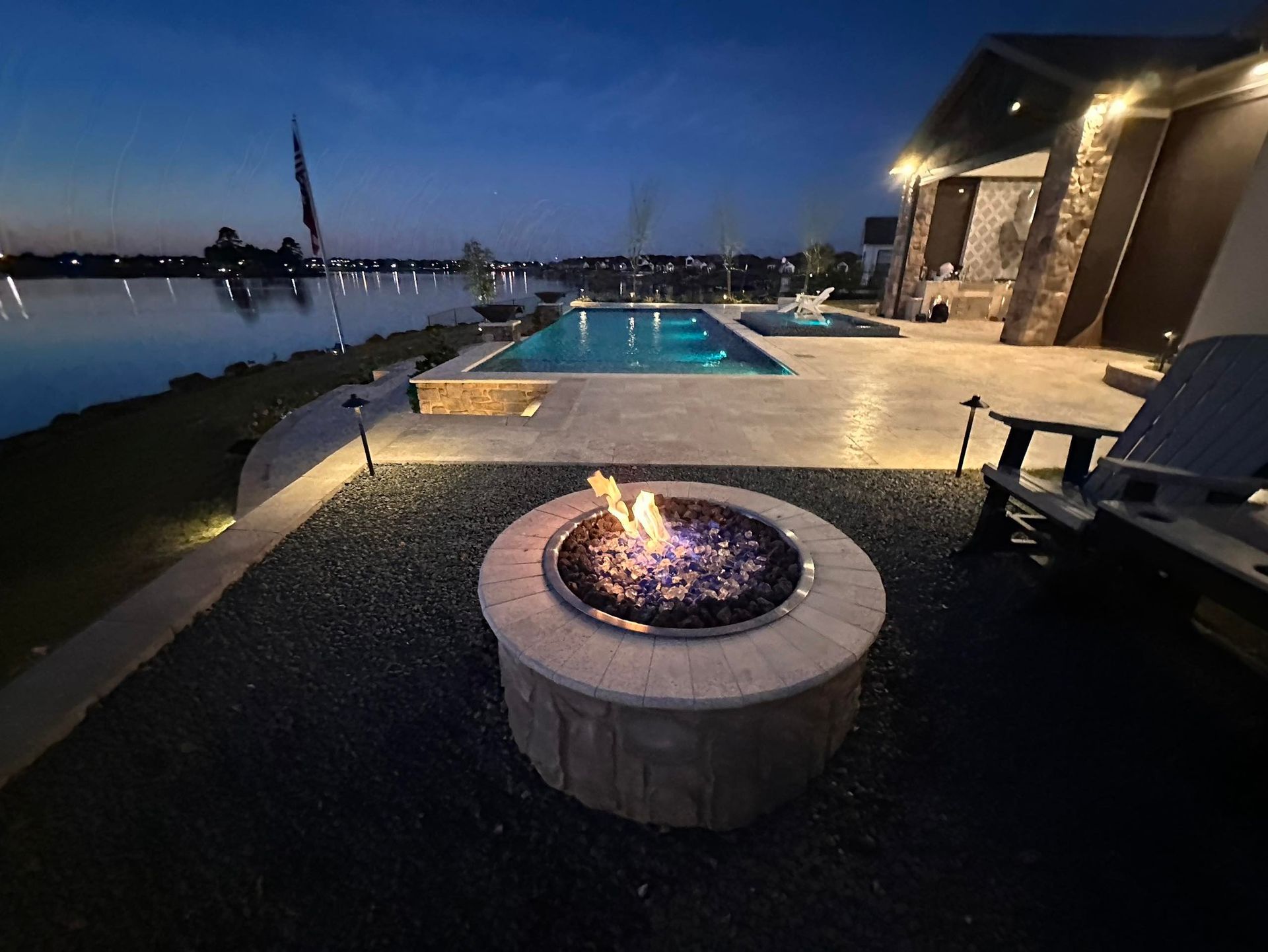 A fire pit in front of a swimming pool at night.